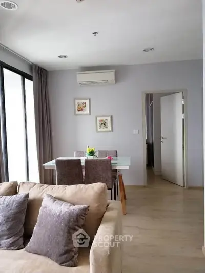 Modern living room with cozy sofa and elegant dining area, featuring stylish decor and ample natural light.