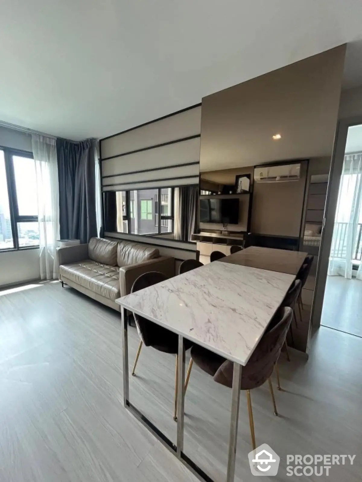 Modern living room with sleek furniture and large windows offering city views.