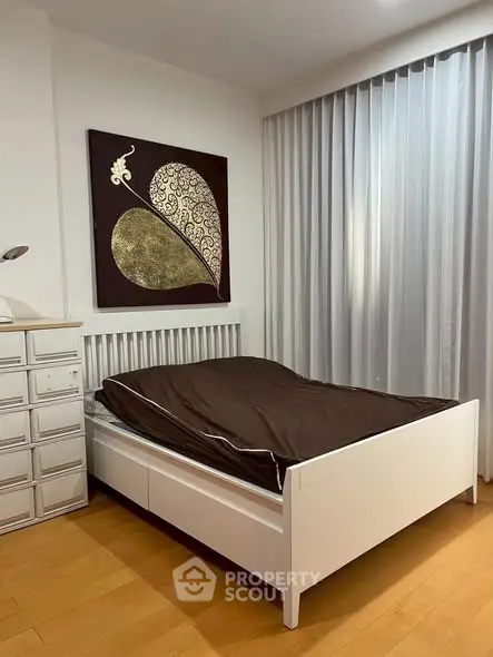 Modern bedroom with stylish decor and natural light, featuring a cozy bed and elegant artwork.