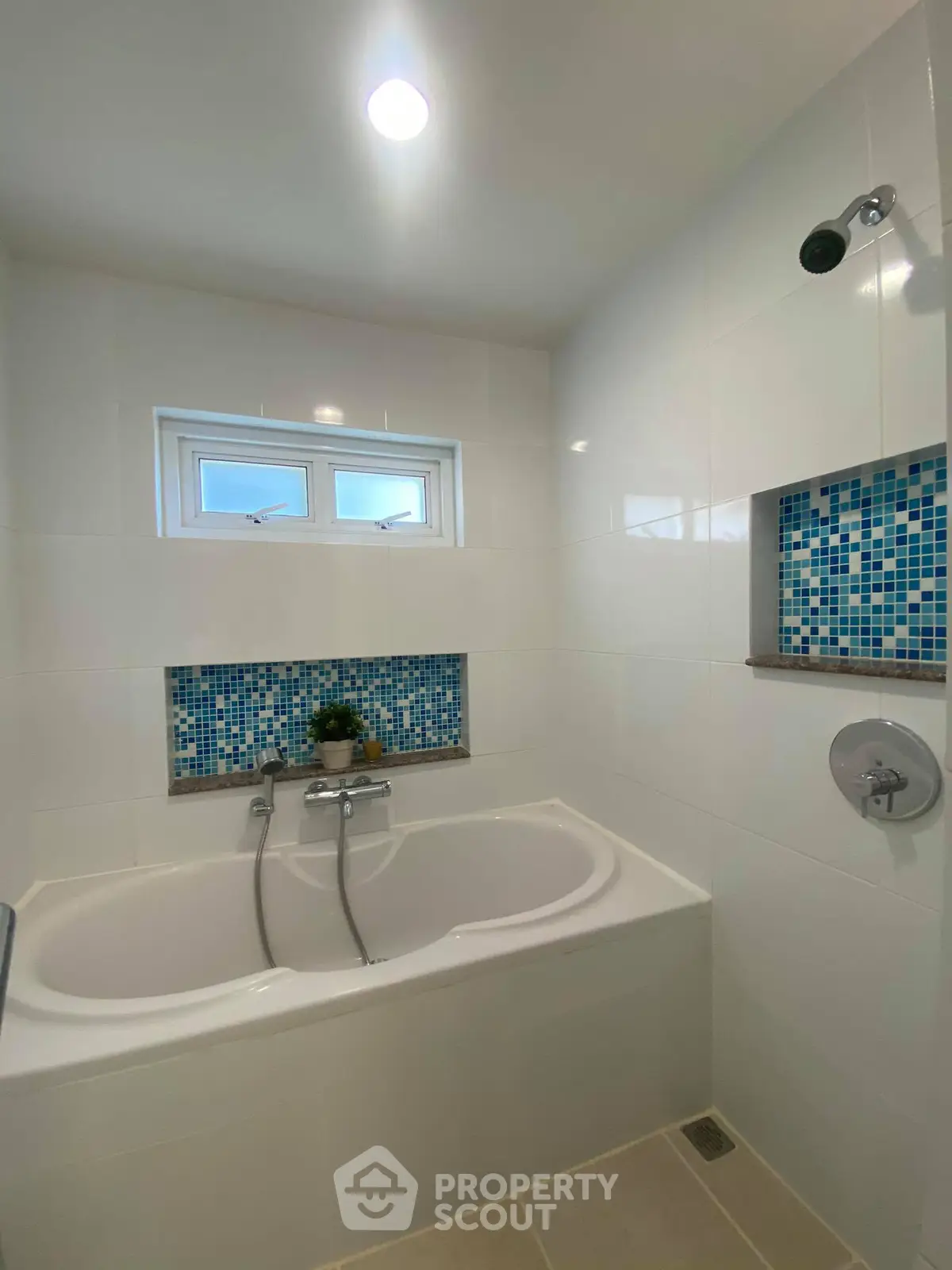 Modern bathroom with stylish bathtub and blue mosaic tile accents