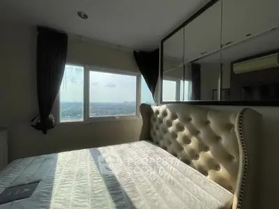 Luxurious bedroom with tufted headboard and panoramic city view from large window.