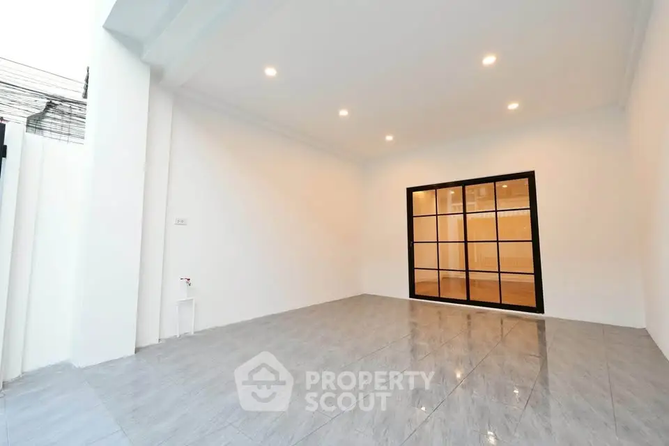 Spacious modern room with sleek tiled flooring and elegant glass doors, perfect for versatile living space.