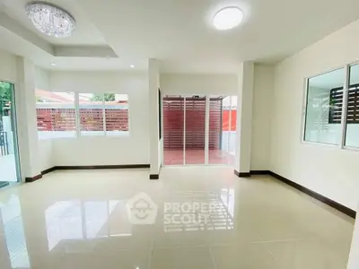 Spacious modern living room with large windows and tiled flooring, perfect for natural light and comfort.