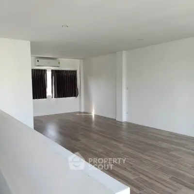 Spacious empty room with wooden flooring and natural light