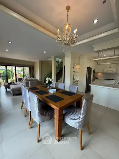 Elegant open-plan living and dining area with chandelier and modern kitchen