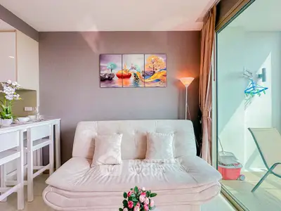 Chic modern living room with cozy sofa and vibrant wall art, adjacent to a sunlit balcony.
