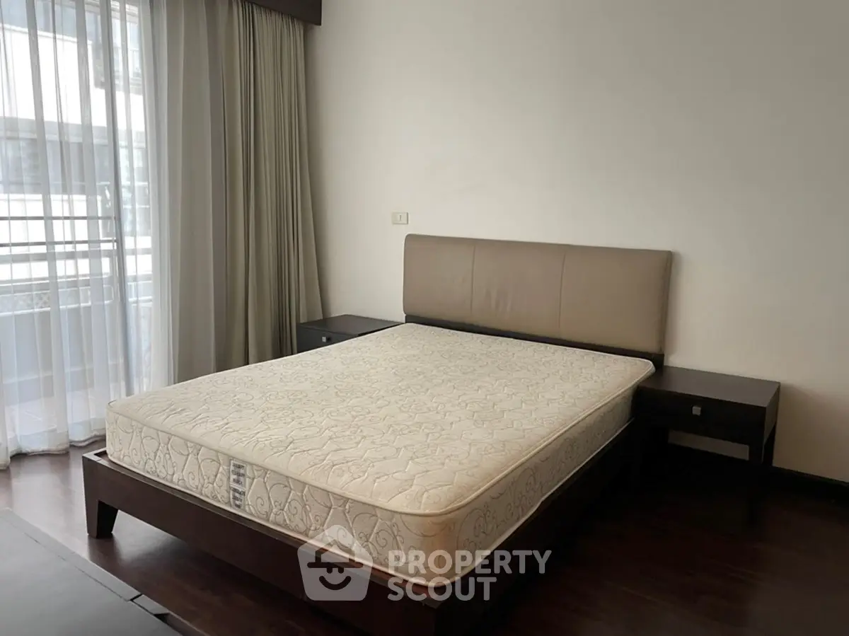 Spacious bedroom with modern bed and natural light from large window in a stylish apartment.