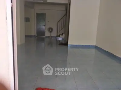 Spacious empty room with tiled floor and staircase, ideal for customization.