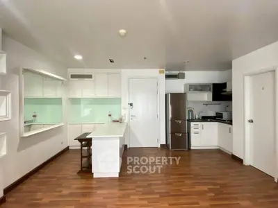 Modern kitchen with sleek white cabinets and stainless steel appliances in open layout apartment.