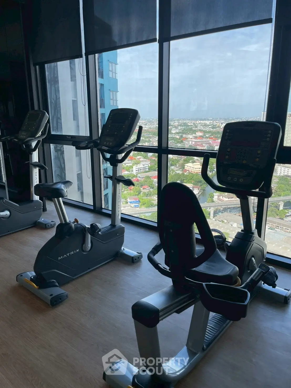Modern gym with exercise bikes and panoramic city view, perfect for fitness enthusiasts seeking luxury amenities.