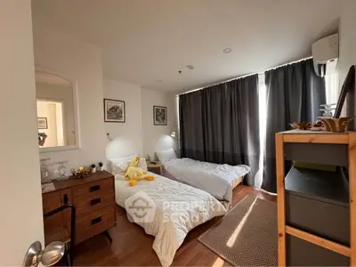Cozy bedroom with twin beds, wooden furniture, and natural light through large windows.