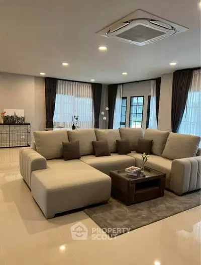 Spacious modern living room with elegant sectional sofa and large windows.