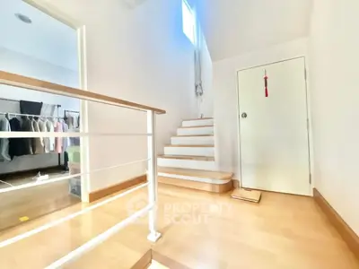 Bright hallway with wooden stairs and modern railing leading to a cozy bedroom.