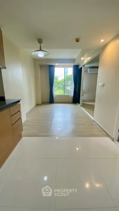 Spacious modern living room with large window and sleek flooring, perfect for urban living.