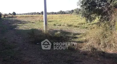 Expansive open land with lush greenery and distant hills, perfect for development opportunities.