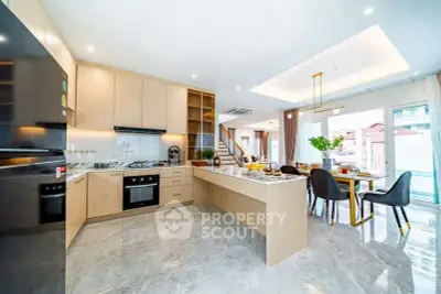 Spacious modern kitchen with open layout and dining area, featuring sleek cabinetry and marble flooring.