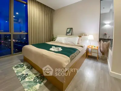Cozy bedroom with a large comfortable bed, modern furnishings, and a stunning night view through floor-to-ceiling windows, perfect for urban living.