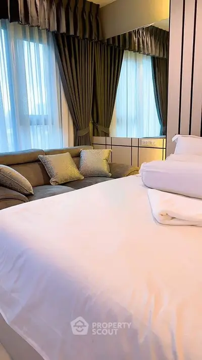 Luxurious bedroom with elegant curtains and cozy seating area, perfect for relaxation.