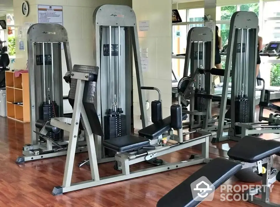 Modern gym with state-of-the-art fitness equipment and wooden flooring in a residential complex.