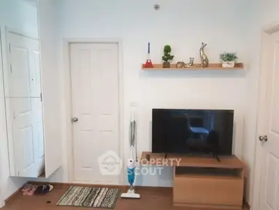 Modern living room with TV, shelf decor, and sleek vacuum cleaner