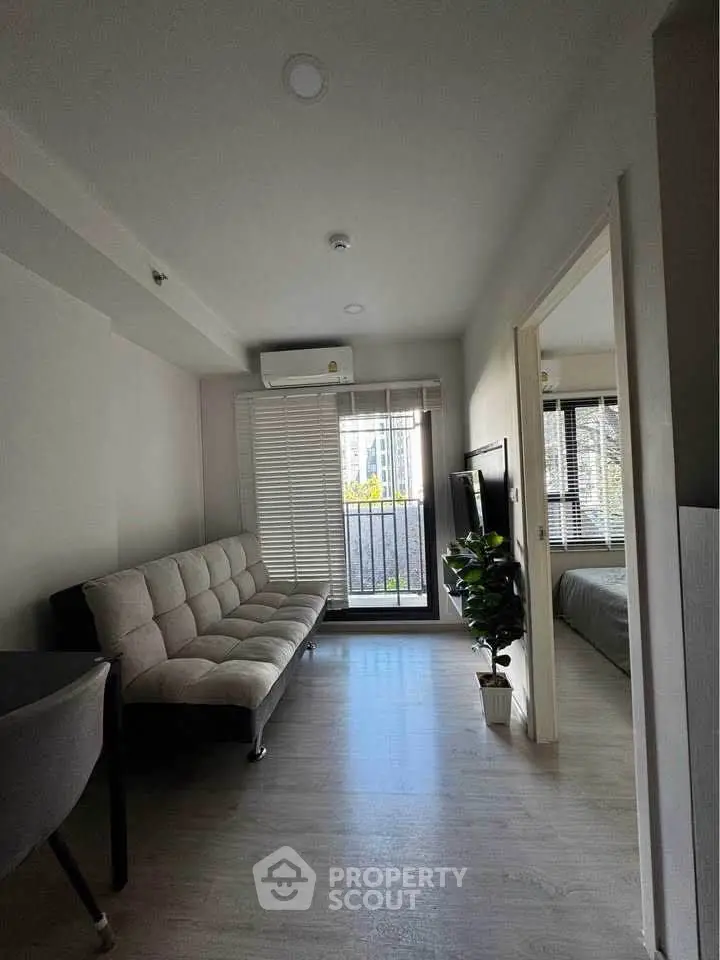 Modern living room with natural light and city view, featuring a cozy sofa and sleek decor.