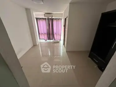 Spacious empty room with tiled flooring and large window with curtains, ideal for customization.