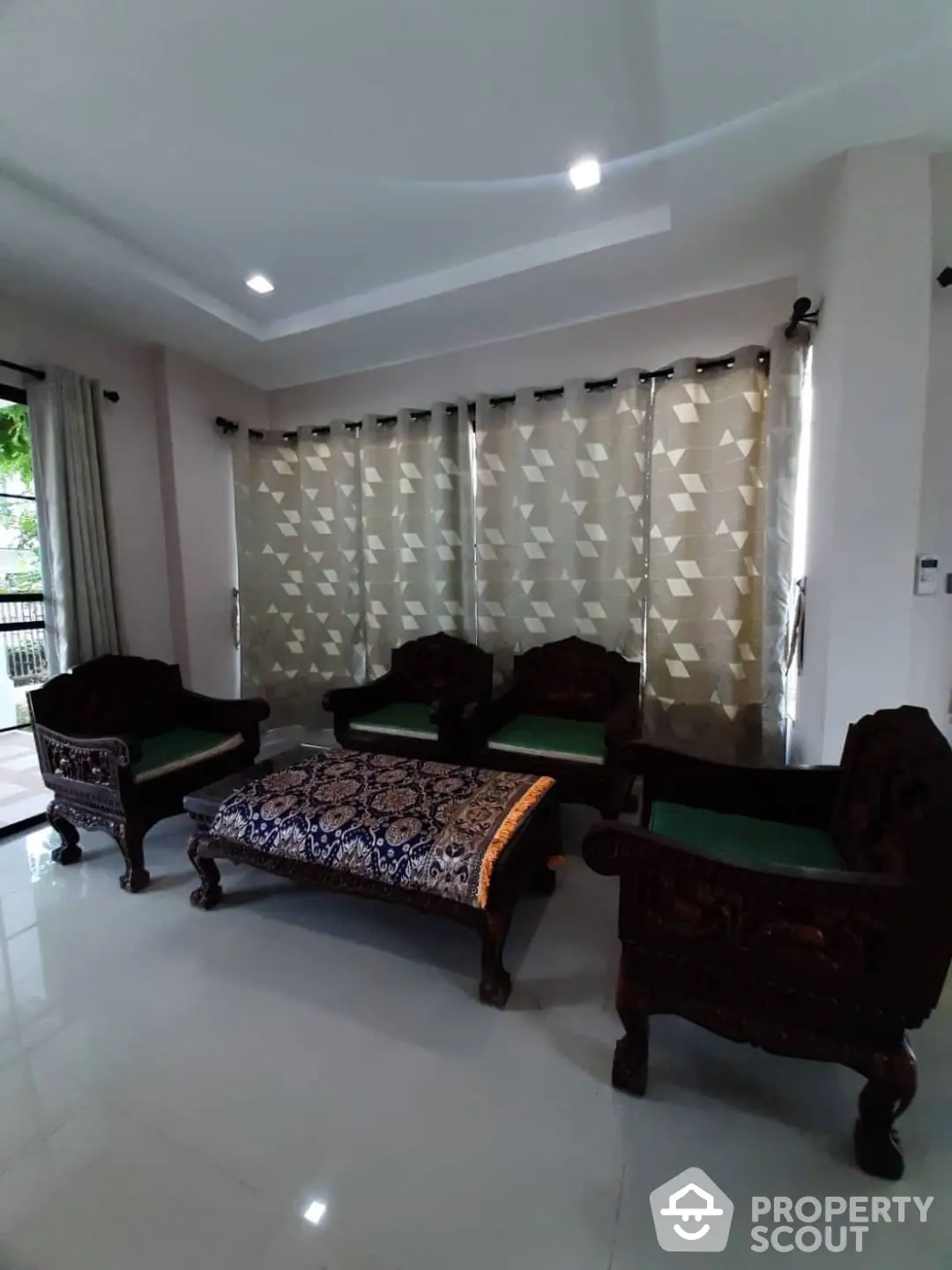 Spacious living room with polished tile flooring and elegant dark wood furniture, complemented by modern recessed lighting and stylish drapery.