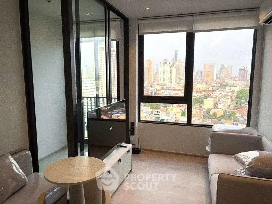 Modern living room with city view, featuring sleek furniture and large windows.
