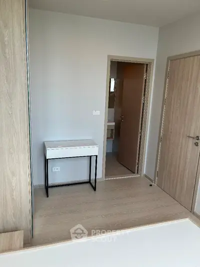 Modern minimalist bedroom with light wood flooring and compact desk