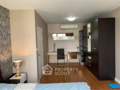 Spacious bedroom with modern furniture and elegant decor, featuring a study area and ample storage space.