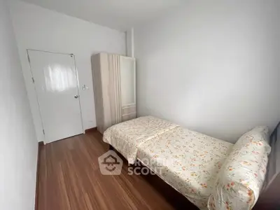 Cozy single bedroom with wooden flooring and floral bedding in a minimalist design.