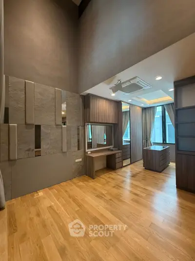 Spacious modern bedroom with wooden flooring and large windows offering ample natural light.
