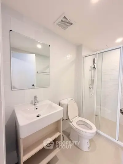 Modern bathroom with sleek white fixtures and glass shower enclosure