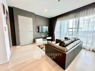 Modern living room with sleek furniture and large windows offering city views.