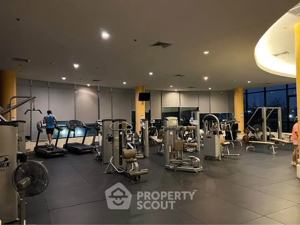 Spacious modern gym with state-of-the-art equipment and large windows offering a scenic view.