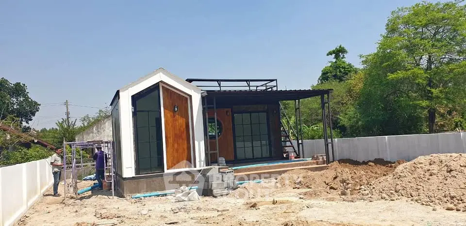 Modern single-story house with unique architecture and spacious yard under clear blue sky.
