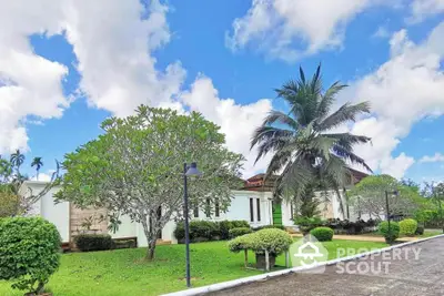 Stunning tropical villa with lush garden and palm trees under a bright blue sky.