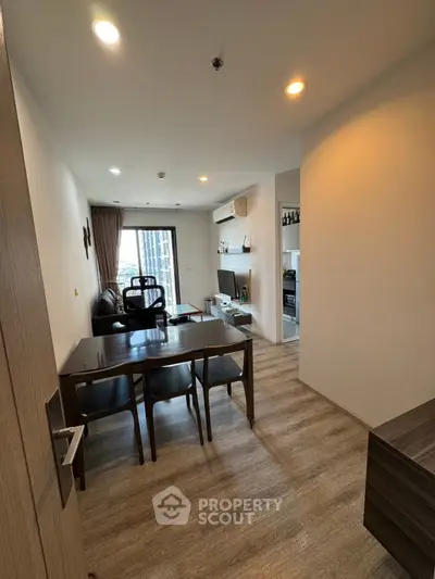 Modern living room with dining area and city view, featuring sleek furniture and wooden flooring.