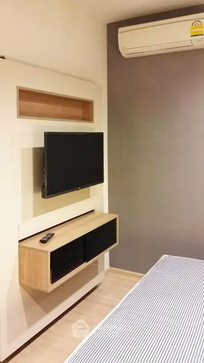 Modern bedroom with wall-mounted TV and air conditioning unit
