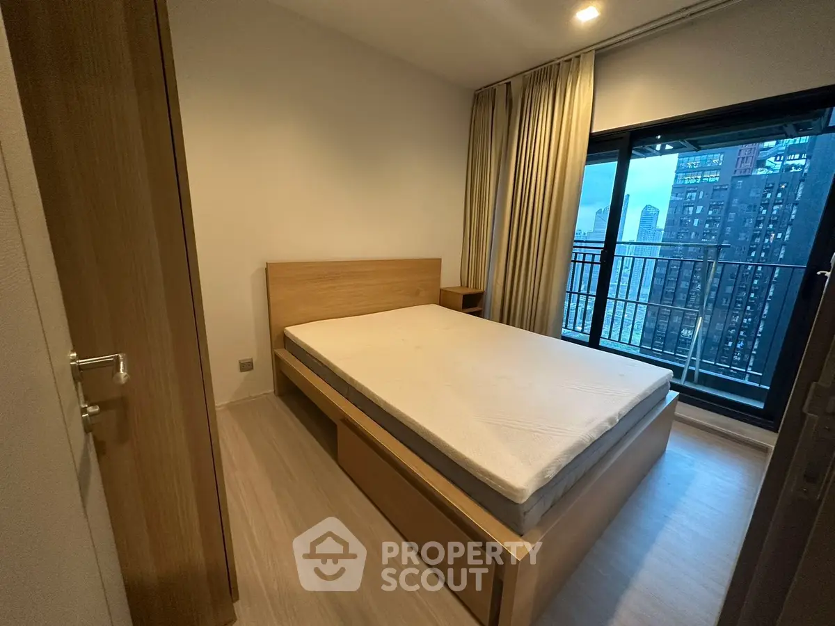 Modern bedroom with city view and balcony access, featuring a wooden bed frame and minimalist design.
