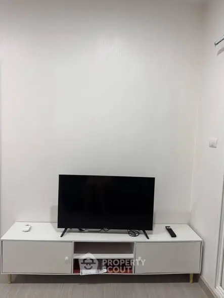 Modern minimalist living room with sleek TV stand and flat-screen TV.