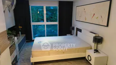 Spacious bedroom with large window and modern decor, offering serene views and ample natural light.