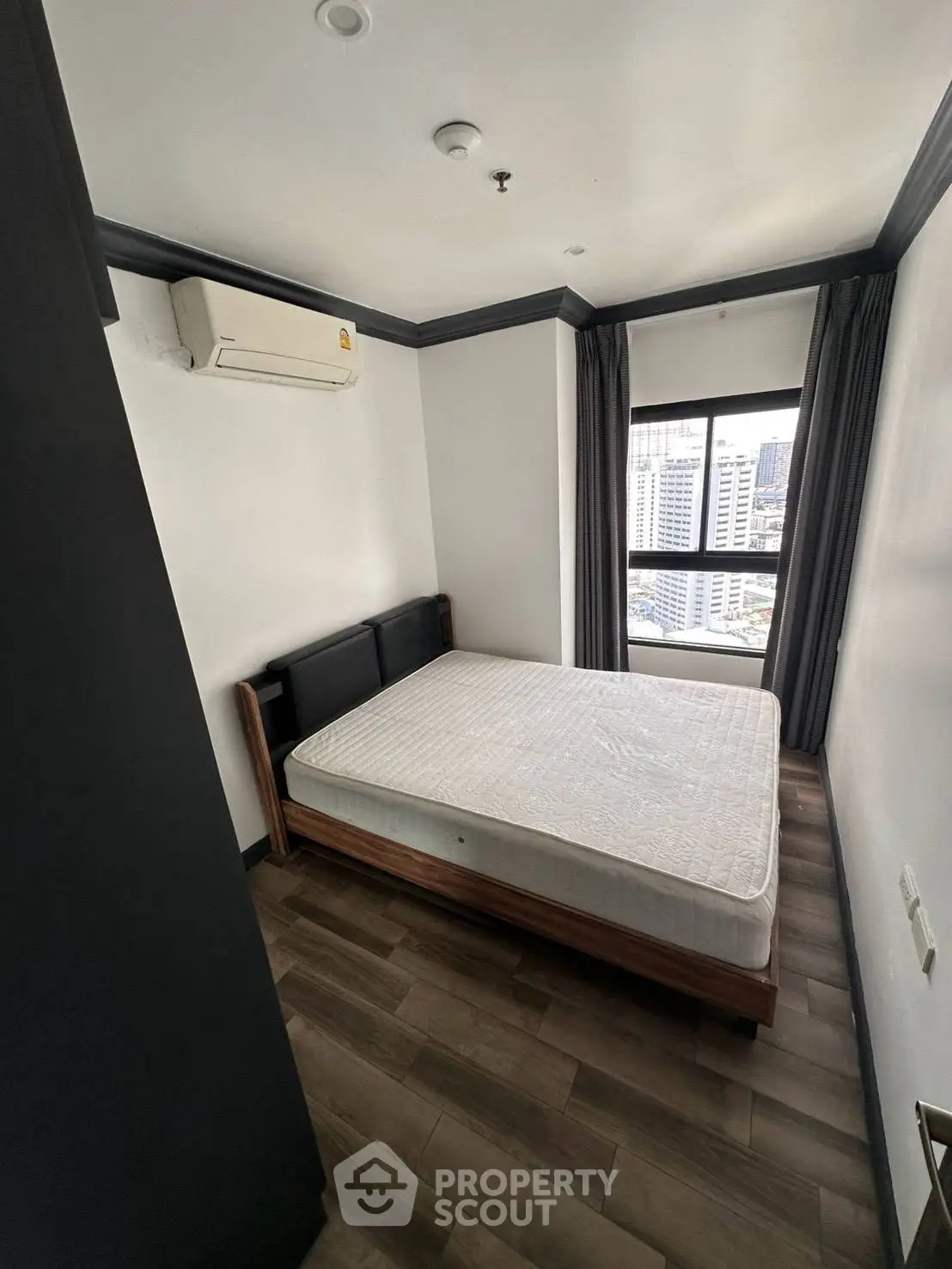 Modern bedroom with city view, featuring a comfortable bed and air conditioning, perfect for urban living.