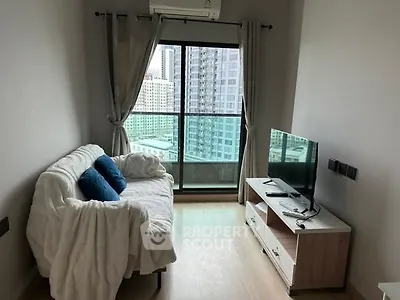 Cozy living room with city view, featuring a comfortable sofa and modern TV setup.