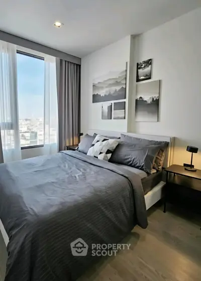 Modern bedroom with large window and stylish decor in urban apartment.