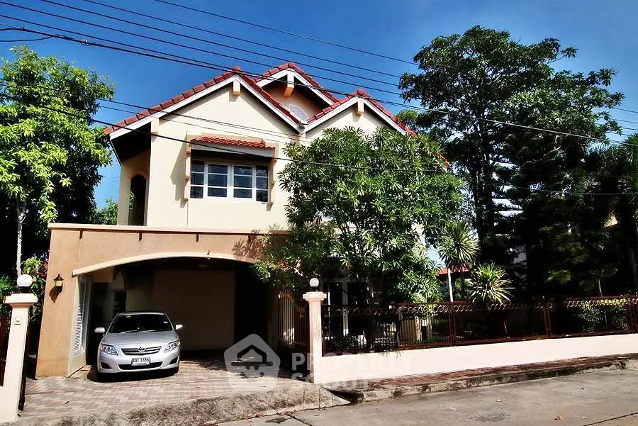 Charming two-story house with lush garden and carport in a serene neighborhood.