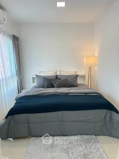 Modern bedroom with cozy bedding and stylish floor lamp, perfect for relaxation.