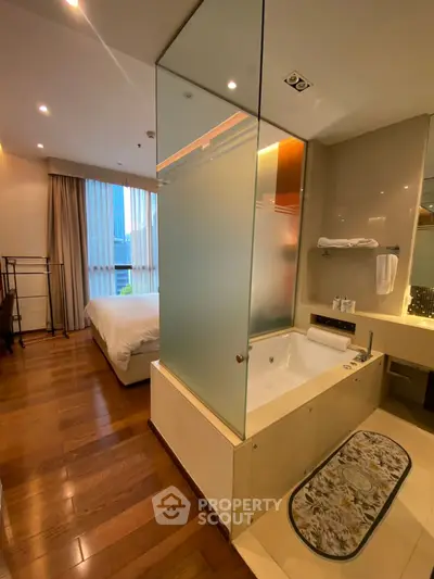 Luxurious modern bedroom with ensuite bathroom featuring elegant bathtub and wooden flooring.