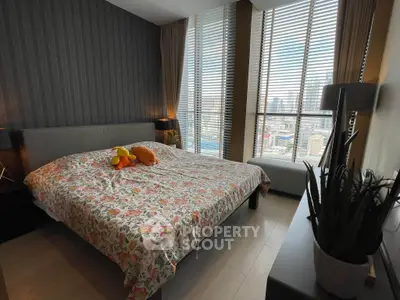 Spacious bedroom with large windows and city view, featuring modern decor and floral bedding.