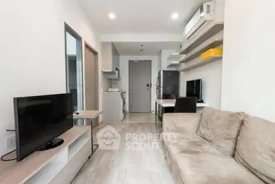 Modern living room with cozy sofa, TV, and open kitchen layout in a stylish apartment.